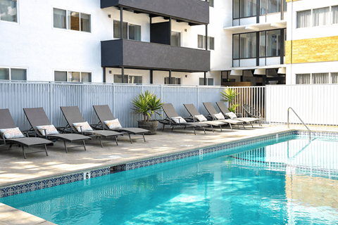 A pool with lounge chairs in front of a building.