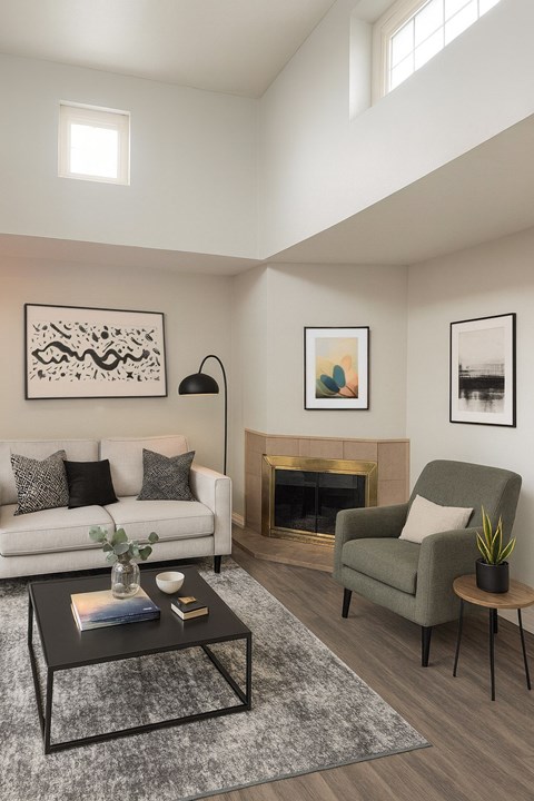 A living room with a white couch, a green armchair, a coffee table, and a fireplace.
