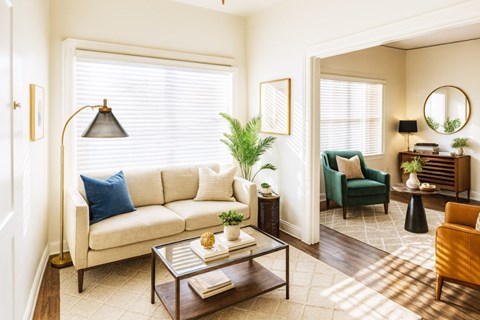 A living room with a white sofa, a green armchair, a coffee table, and a lamp.