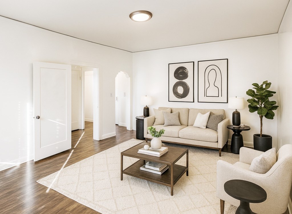 A living room with a white couch, a coffee table, and a plant.