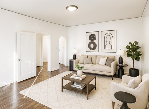 A living room with a white couch, a coffee table, and a plant.