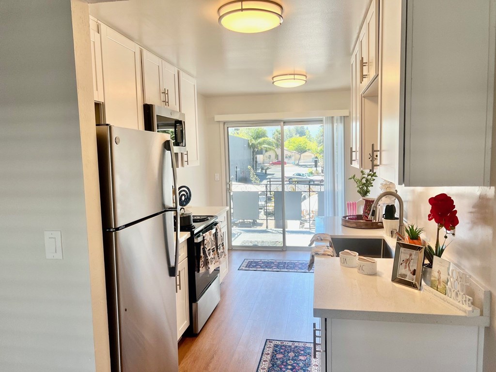 a kitchen with stainless steel appliances and a door to a balcony