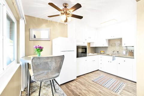 A kitchen with a white chair and a ceiling fan.