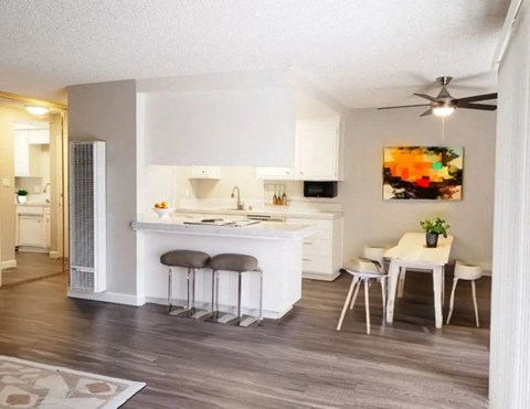 A kitchen with white cabinets and a bar area with stools.
