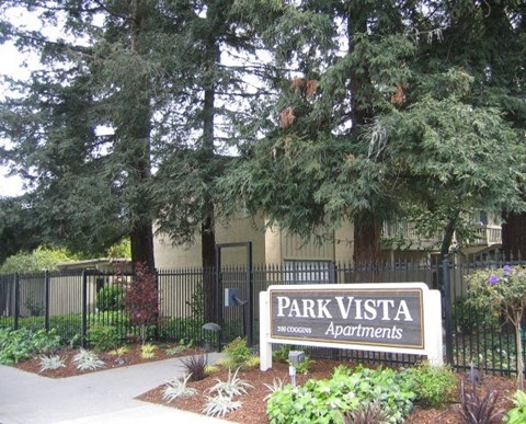 a park vista apartments sign in front of a fence and trees