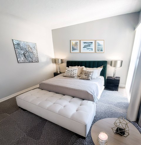 A bedroom with a large bed and a bench.