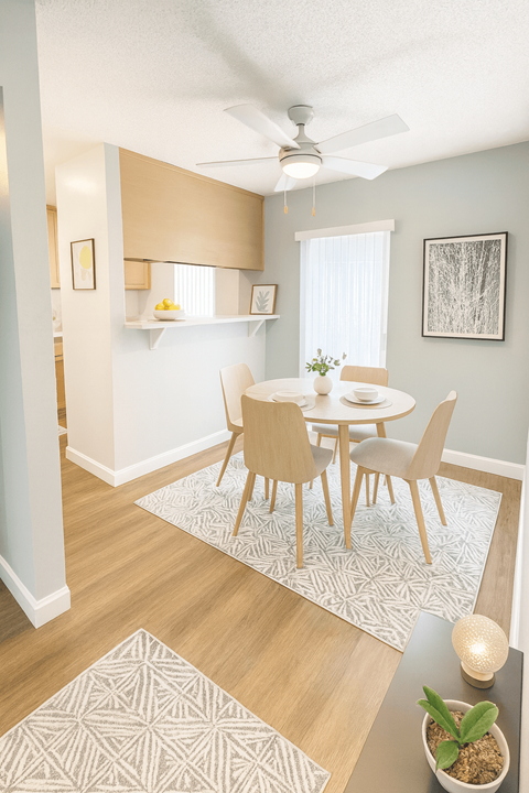 A dining room with a table set for two and a ceiling fan.