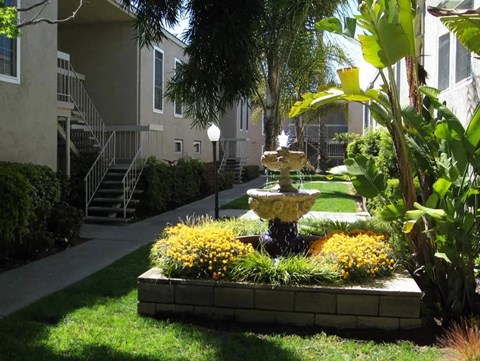 a fountain in a garden in front of an apartment building