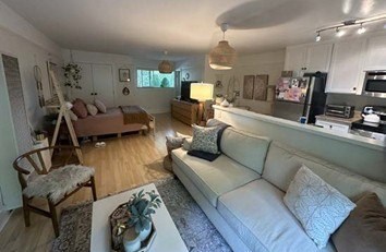 A living room with a white couch, a wooden chair, and a coffee table.