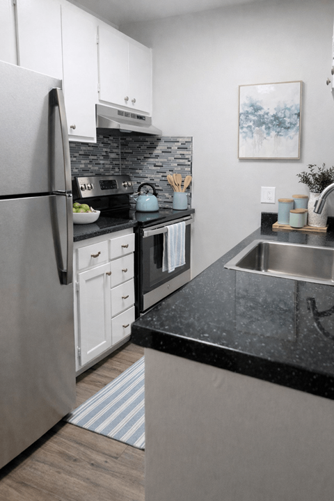 A modern kitchen with a black countertop and stainless steel appliances.