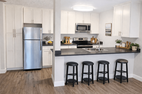 A kitchen with white cabinets and a stainless steel refrigerator.