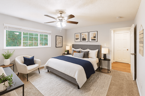 A bedroom with a bed, chair, and a ceiling fan.
