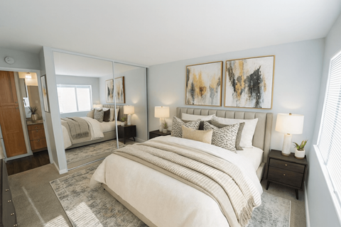 A bedroom with a large bed and a painting on the wall.