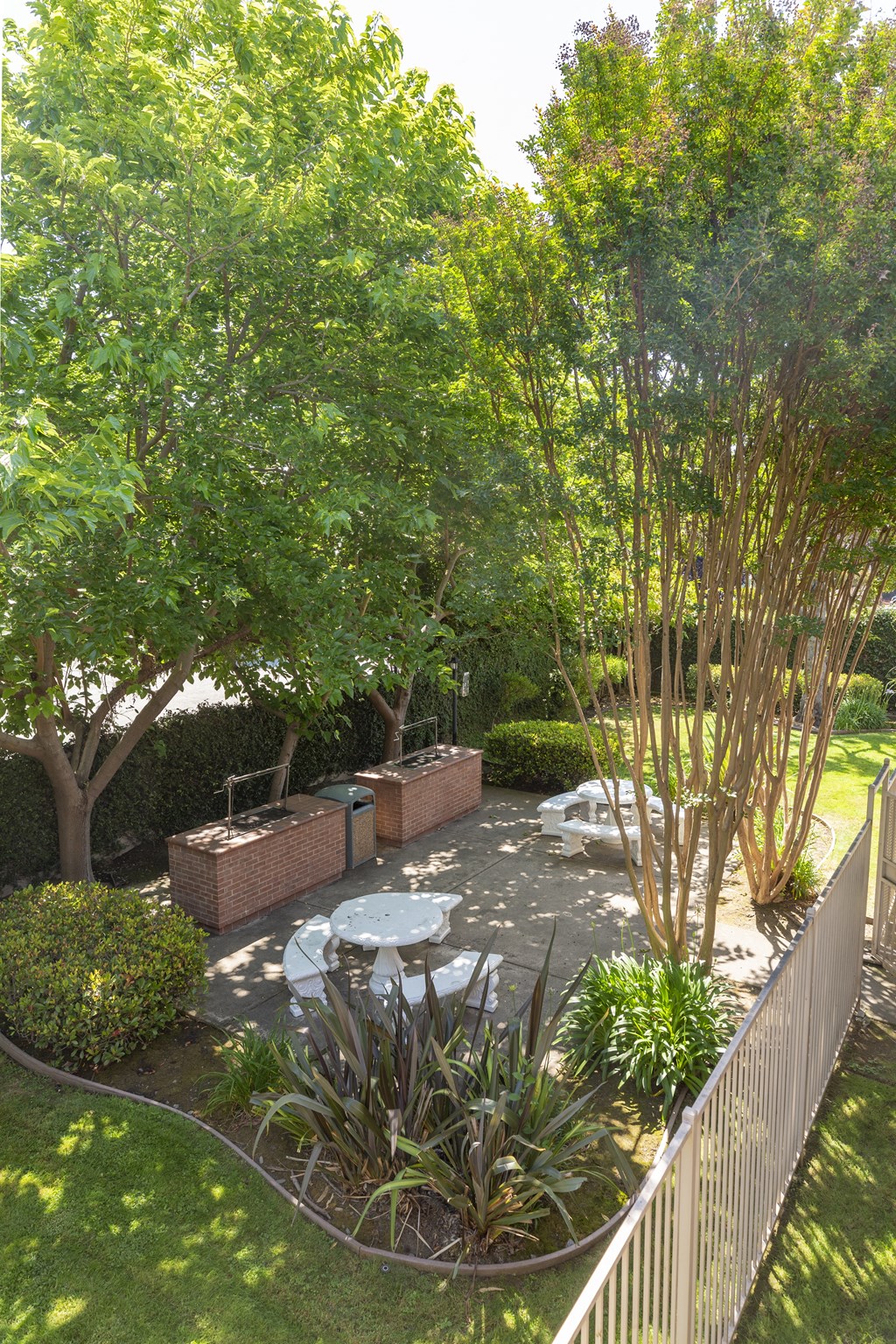 a backyard with a patio and trees and a white fence