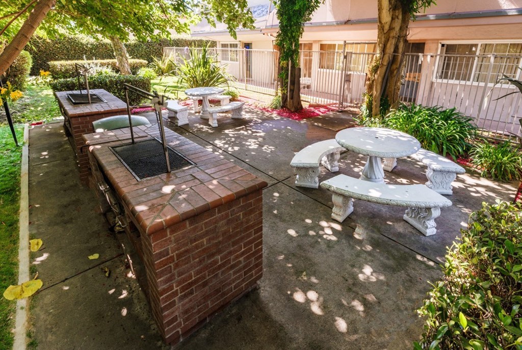 a patio with a barbecue grill and tables