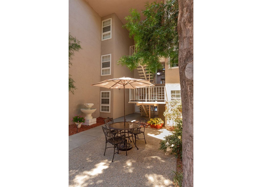 A patio with a table and chairs under an umbrella.