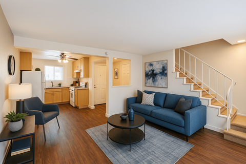 A living room with a blue couch and a staircase.