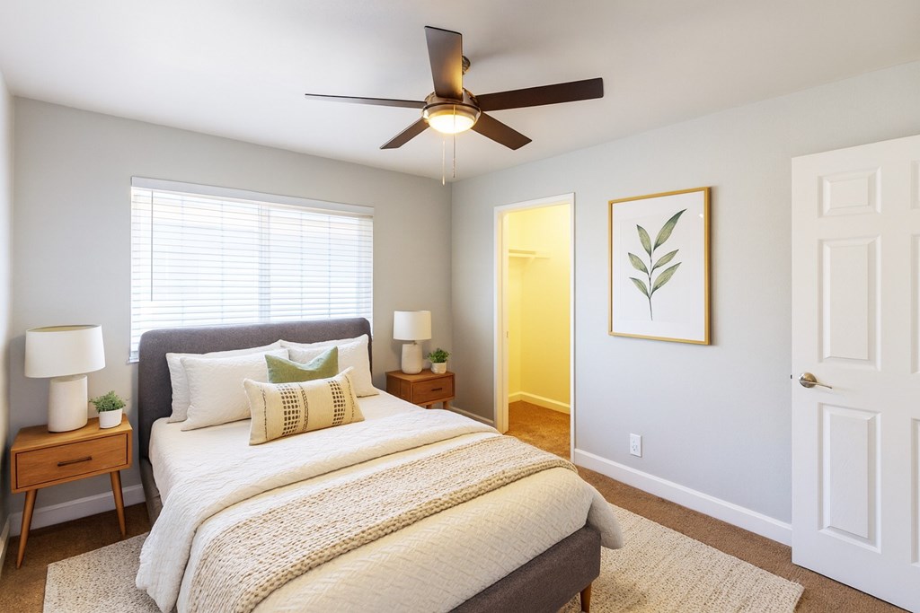 A bedroom with a bed, two lamps, and a ceiling fan.