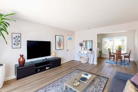 A living room with a television, a coffee table, and a dining table.