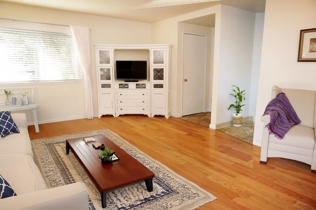 A living room with a white couch, a wooden coffee table, and a white entertainment center.