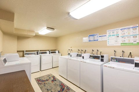 A laundromat with washers and dryers lined up.