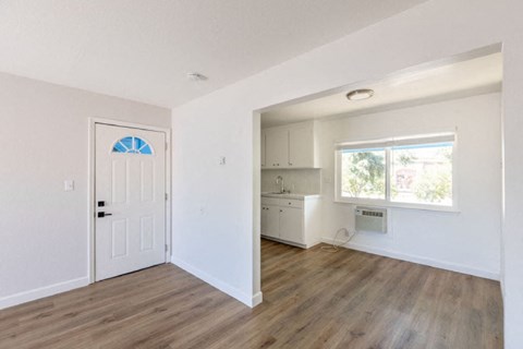 A room with a white door and a window with a view of trees.