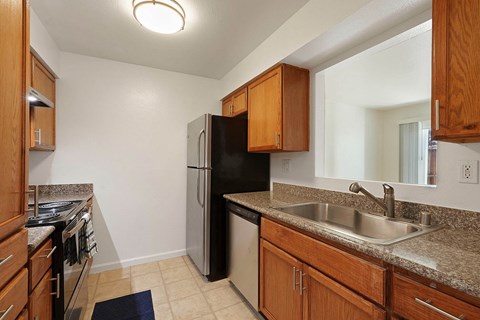 A kitchen with a black refrigerator and wooden cabinets.