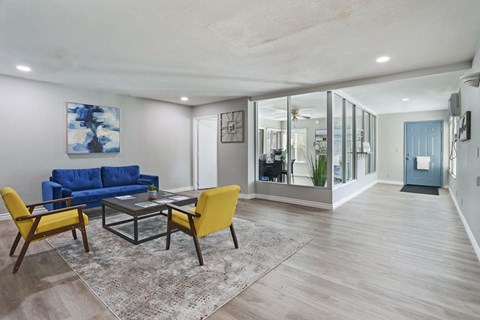 A living room with a blue couch and yellow chairs.