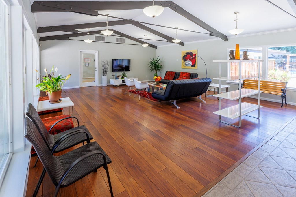 A living room with a black couch and wooden floors.
