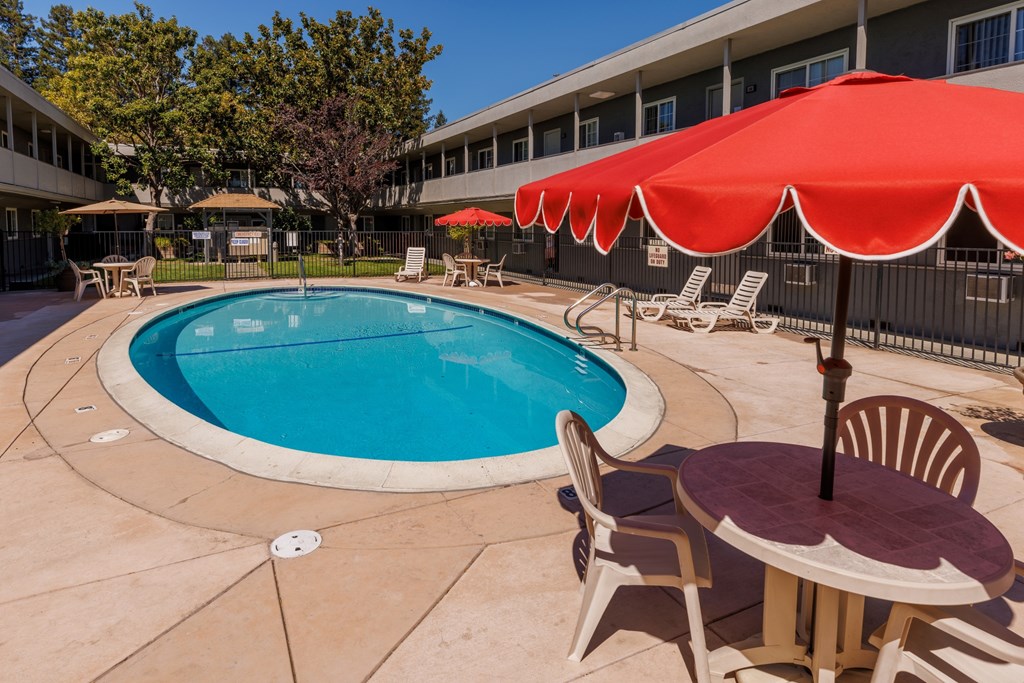 A pool with a table and chairs and umbrellas.