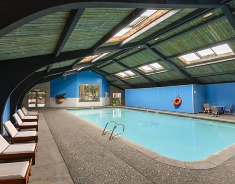 A large indoor swimming pool with sunroofs and lounge chairs.