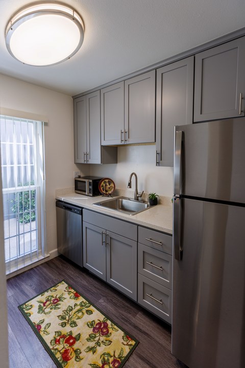 A kitchen with a refrigerator, sink, and cabinets.