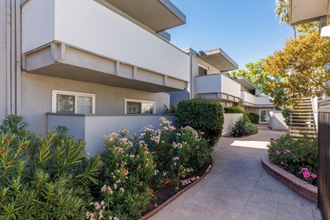 A white building with a garden in front.