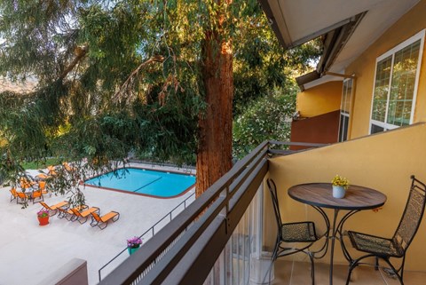 A patio with a table and chairs overlooking a pool.