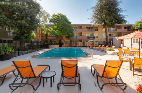 A pool surrounded by orange chairs and tables.