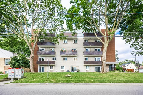 A large apartment building with multiple balconies and trees in front.