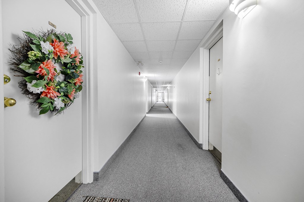 a long white corridor with white walls and a wreath on the wall