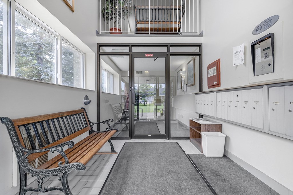 A wooden bench sits in front of a glass door.