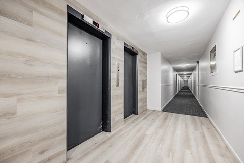 A long hallway with wood floors and white walls.