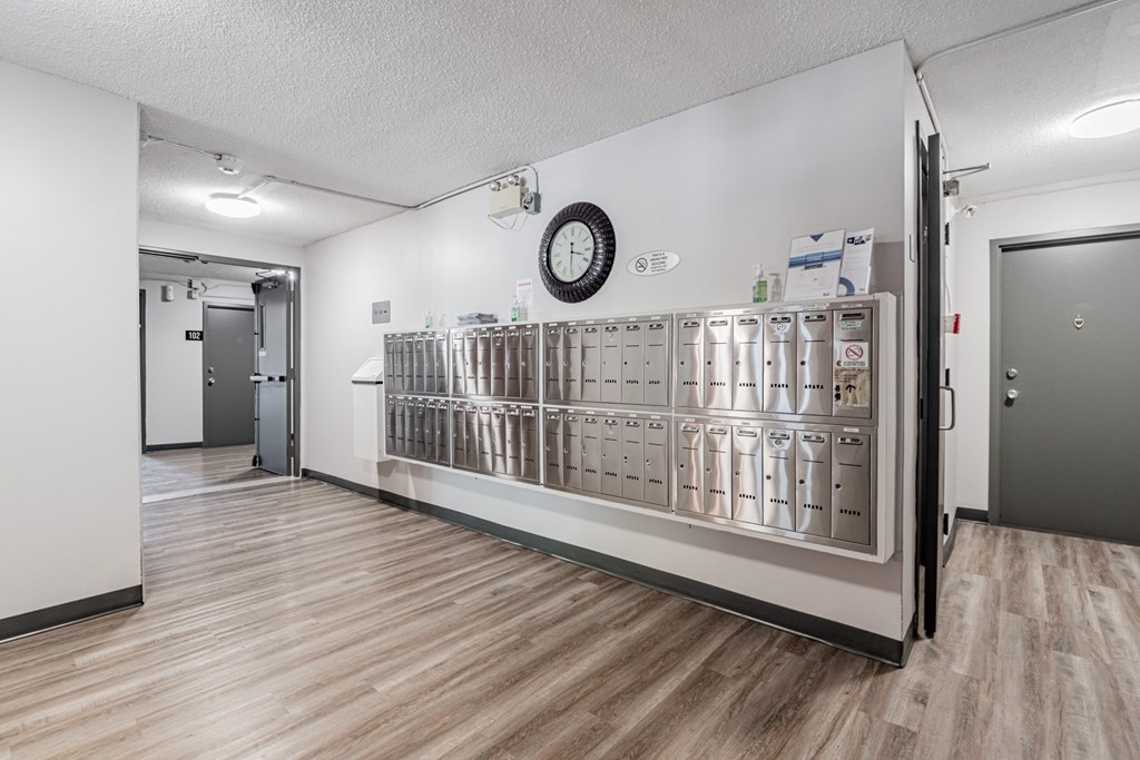 A room with a large metal fridge and a clock on the wall.