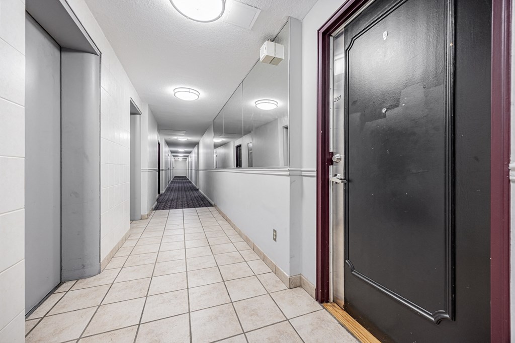 A long hallway with doors on both sides and a black door on the right.