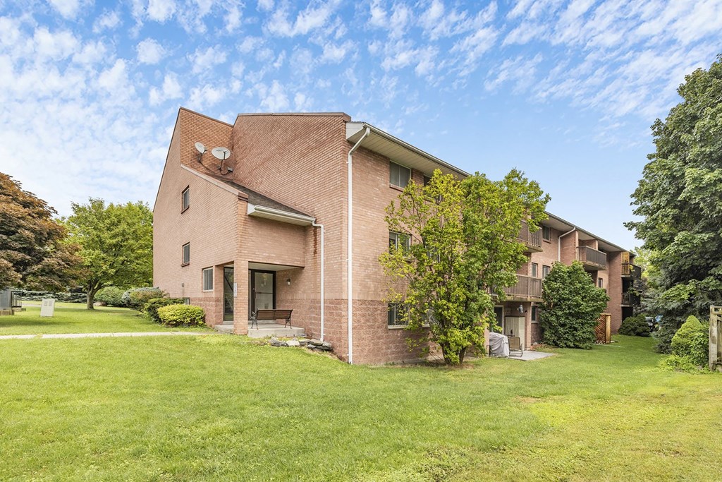 A large brick house with a green lawn in front.