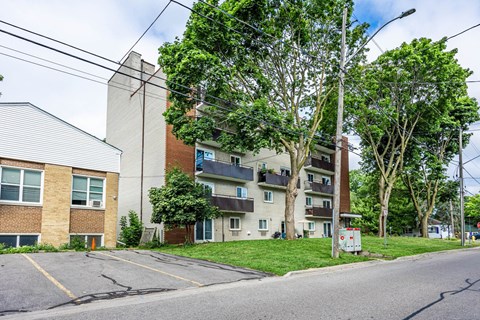 A street view of a residential area with apartment buildings and trees.