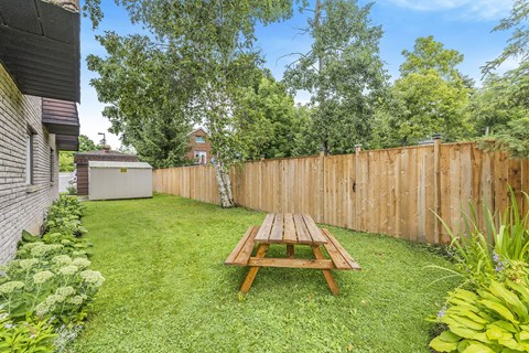 A backyard with a picnic table and a wooden fence.