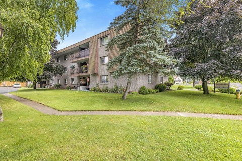 A grassy area in front of a building with a tree on the right.