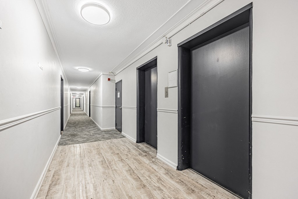 A long hallway with black doors on the right side.