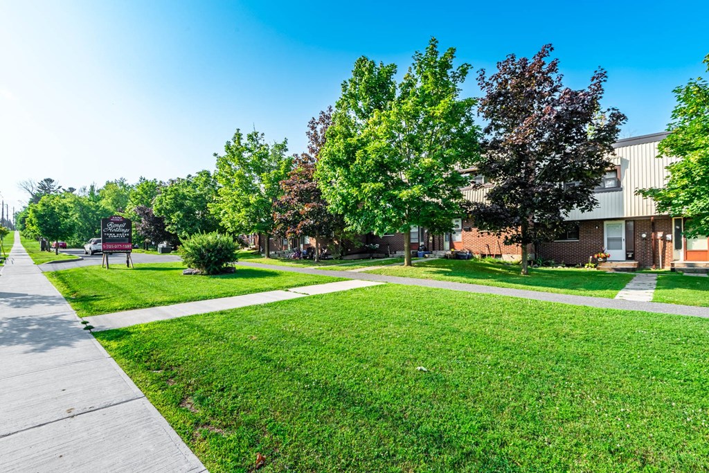 A residential area with a house, trees, and a sidewalk.