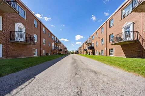 A long, straight road separates two rows of apartment buildings.