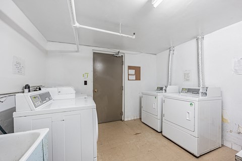 A room with two washing machines and a door.