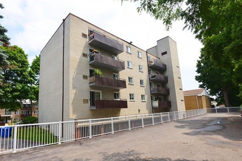 A large concrete building with balconies and a white fence in front.